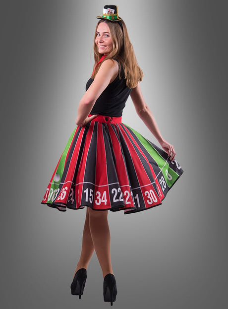 Eine Frau in High Heels trägt das „Tellerrock Roulette Rad“ – ein Kleid mit Roulette-Rad-Muster –, dazu einen kleinen, passenden Hut. Vor einem grauen Hintergrund verkörpert sie den Glamour einer Casino-Glücksfee, die sich für eine Las-Vegas-Mottoparty fertig gemacht hat.