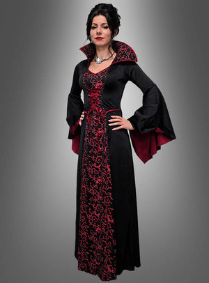 Vor einem grauen Hintergrund steht eine Frau, die das Kleid „Vampir Königin Mina Damen“ trägt – ein langes schwarz-rotes Kleid im Gothic-Stil mit ausgestellten Ärmeln und hohem Kragen.