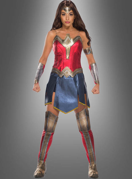 Eine Person, die das Deluxe-Wonder-Woman-Kostüm trägt, steht mit leicht angewinkelten Armen und geballten Fäusten nach vorne gerichtet und verkörpert vor einem schlichten grauen Hintergrund die Stärke der legendären DC-Superheldin.
