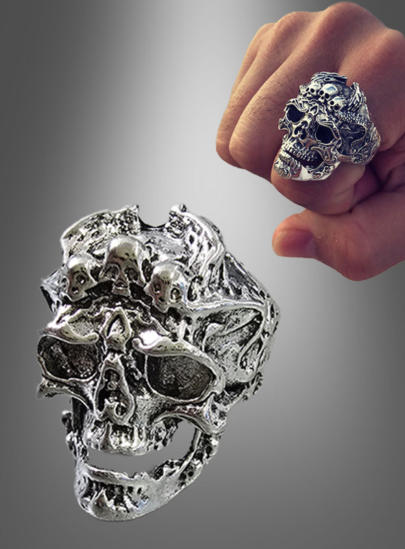 Der verstellbare Totenkopf-Ring in Silber mit seinem aufwendig gestalteten Totenkopfmotiv wird sowohl einzeln als auch an einer Hand vor einem grauen Farbverlaufshintergrund präsentiert – damit ist er ein ideales Halloween-Schmuckstück oder ein auffälliges Accessoire für den Alltag.