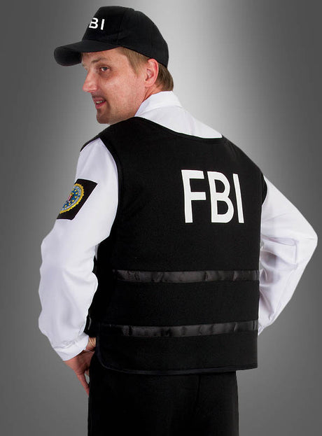 Ein Mann, der das FBI-Herren-Komplettkostüm trägt, steht mit dem Rücken zur Kamera, wodurch der auffällige FBI-Schriftzug auf seiner Weste vor einem neutralen grauen Farbverlauf besonders gut zur Geltung kommt – die perfekte Inspiration für alle, die einen authentischen Agenten-Look suchen.