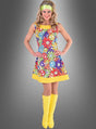 Eine Frau, die das Hippie-Blumenkleid „Smile“ trägt – ein farbenfrohes, von den 1960er Jahren inspiriertes Kleid, verziert mit Peace-Zeichen und Blumen –, kombiniert mit einem gelben Stirnband und gelben kniehohen Stiefeln, strahlt vor dem grauen Hintergrund echtes „Flower Power“ aus und ist damit die ideale Wahl für jede 70er-Jahre-Party.