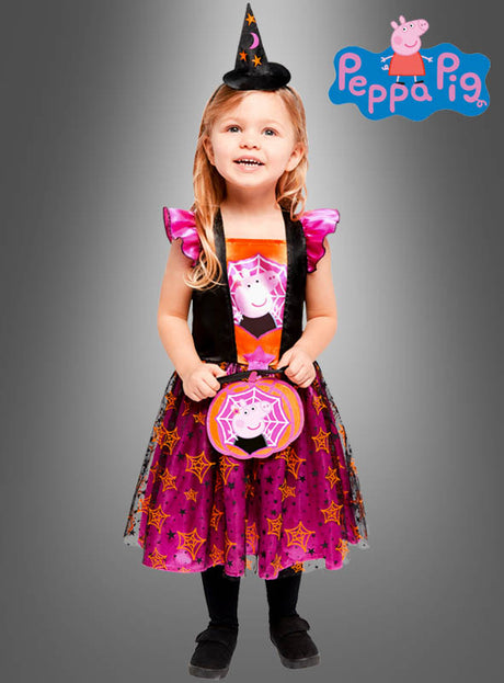Ein kleines Mädchen trägt das Peppa-Pig-Kostüm „Hexe“, das aus einem Kleid mit Sternenmuster von Peppa Wutz, einem passenden Hexenhut und einer Handtasche besteht. Sie steht vor einem grauen Hintergrund mit dem Peppa-Pig-Logo.