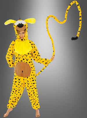 Eine Person trägt das gelbe Marsupilami-Kostüm für Erwachsene mit Flecken, das einen langen Schwanz, große Ohren und ein karikaturhaftes Gesicht aufweist; sie steht barfuß vor einem grauen Hintergrund mit Farbverlauf.