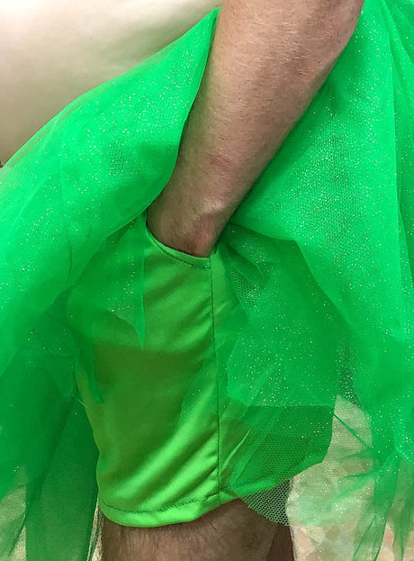 Jemand, der das „Trinkerbelly dicke Fee“-Männerkostüm mit Perücke trägt – mit seinem leuchtend grünen Tutu und den dazu passenden Shorts, die den nackten Oberkörper und die Arme betonen –, ist die perfekte Wahl als lustiges Feen-Kostüm für Männer oder als urkomisches Junggesellenabschied-Kostüm.