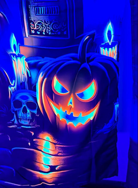 Eine leuchtende Kürbislaterne, ein Totenkopf und brennende Kerzen werden in einer gruseligen Halloween-Szene von blauem und orangefarbenem Licht beleuchtet – perfekt zur Dekoration mit der waschbaren Fotowand „Halloween Schloss und Friedhof“ (120 x 185 cm) als gruselige Wanddekoration oder unheimliche Halloween-Szene, insbesondere wenn sie durch UV-Schwarzlicht-Effekte ergänzt wird.