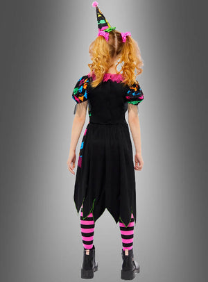 Ein Kind steht mit dem Rücken zur Kamera vor einem grauen Hintergrund mit Farbverlauf und trägt das „Zirkus Clown Neon Kostüm Mädchen“ – bestehend aus einem schwarzen Kleid mit bunten Ärmeln, einer gestreiften rosa-schwarzen Strumpfhose und einem spitzen Hut – und ist damit perfekt für den Kinderfasching gerüstet.