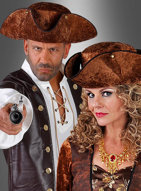 Zwei Erwachsene in braunen Piratenkostümen und -hüten; ein Mann, gekleidet wie ein Musketier und mit einem braunen Dreispitz, richtet eine Pistole auf etwas, während die Frau, die eine Halskette trägt und ebenfalls einen braunen Dreispitz auf dem Kopf hat, nach vorne blickt. Beide haben einen ernsten Gesichtsausdruck.