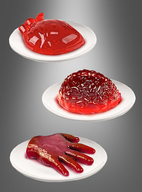 Auf drei weißen Tellern liegen Gelatine-Desserts in Form eines Herzens, eines Gehirns und einer Hand – alle in leuchtendem Rot vor einem grauen Hintergrund mit Farbverlauf. Diese gruseligen Leckereien wurden mit den Halloween-Puddingformen „Herz“, „Gehirn“ oder „Hand“ hergestellt und umfassen einen wackeligen „Gehirn-Wackelpudding“ sowie ein auffälliges „Gelatine-Herz“ – perfekt für eine unheimliche Halloween-Dekoration.