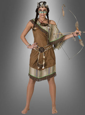 Eine Frau in einem „Indianer-Kostüm“ von Silbermond Damen, das von der Kleidung der amerikanischen Ureinwohner inspiriert ist, hält Pfeil und Bogen in der Hand, während sie barfuß vor einem grauen Hintergrund mit Farbverlauf steht.