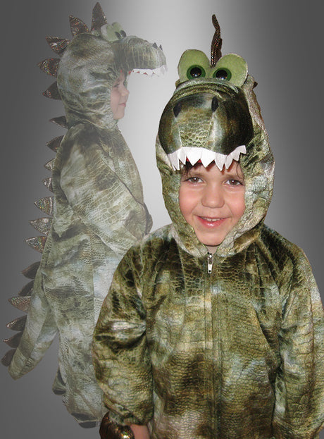 Ein Kind in einem grünen Dinosaurier-Kostüm für Kinder lächelt in die Kamera, während im Hintergrund eine Seitenansicht des Kostüms („Dino-Kostüm“) verblasst zu sehen ist.