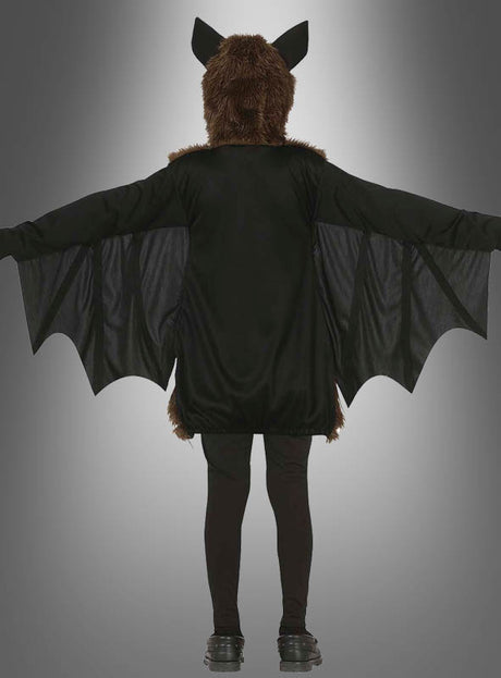 Eine Person, die das Plüsch-Fledermaus-Kostüm für Kinder trägt – mit ausgebreiteten Flügeln, einer pelzigen Kopfbedeckung mit Ohren und schwarzen Leggings –, ist von hinten vor einem grauen Farbverlaufshintergrund zu sehen – damit ist es die ideale Wahl für ein Halloween-Kostüm für Kinder.