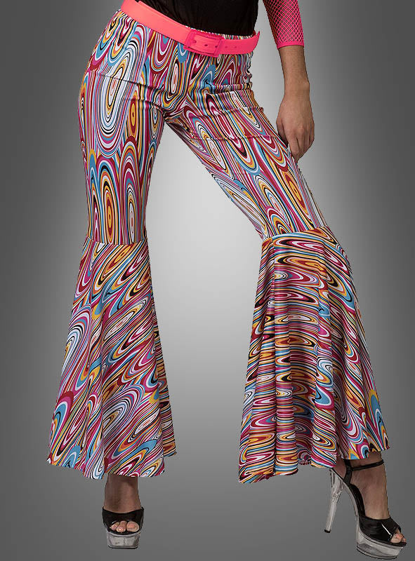 Ein Model präsentiert die schwungvolle Retro-Schlaghose für Damen mit einem lebhaften psychedelischen Muster und klassischem Schlaghosen-Design, kombiniert mit einem rosa Gürtel und silbernen Stöckelschuhen vor einem einfarbigen grauen Hintergrund.