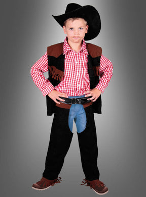 Ein kleiner Junge im Cowboy-John-Kinderkostüm – mit schwarzem Hut, rotem Karohemd, schwarzer Weste, Chaps und braunen Schuhen – steht mit den Händen in die Hüften gestemmt vor einem grauen Hintergrund mit Farbverlauf.