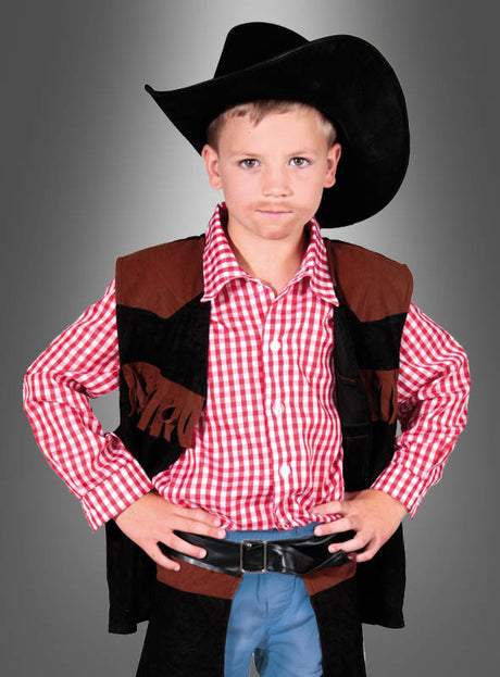 Ein kleiner Junge mit schwarzem Cowboyhut und rot kariertem Hemd steht mit den Händen in den Hüften vor einem neutralen Farbverlaufshintergrund und blickt in die Kamera – damit präsentiert er das Cowboy-John-Kinderkostüm perfekt für den Karneval oder andere Western-Kostümpartys.