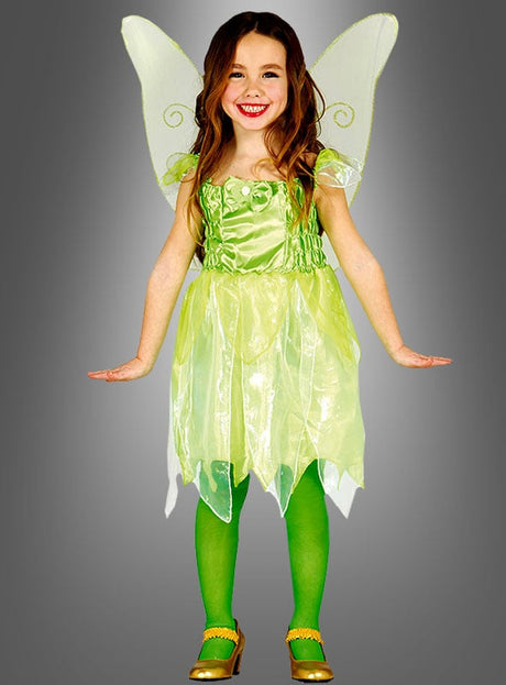 Ein Kind trägt das „Kleine Fee“-Mädchenkostüm mit zarten Flügeln, einem grünen Kleid, passenden grünen Strumpfhosen und goldenen Schuhen und lächelt vor einem grauen Hintergrund mit Farbverlauf – ein zauberhafter Look, perfekt für die Kleinen, die von Magie träumen.
