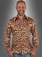 Ein Mann mit Glatze lächelt, während er das „Herrenhemd Leoprint 80er Jahre“ trägt – ein langärmeliges Hemd mit Knopfleiste und auffälligem Leopardenmuster –, dazu blaue Jeans, vor einem grauen Hintergrund mit Farbverlauf.