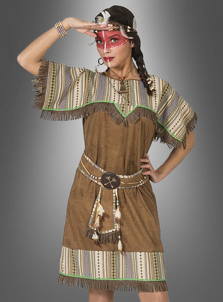 Eine Frau im „Indianerin“-Kostüm von Silbermond in Übergröße – ein braunes, gestreiftes Kleid mit Fransen und Ziergürtel, einem Feder-Stirnband und roter Gesichtsbemalung – posiert mit einer Hand in der Hüfte vor einem grauen Hintergrund. Das perfekte XXL-Wildwest-Damenkostüm für Mottopartys und Veranstaltungen.