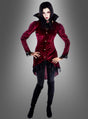 Das Model trägt die „Wandelbare Kostümjacke Vampirin Jasna“, kombiniert mit einer schwarzen Hose und Stiefeln, und steht mit den Händen in den Hüften vor einem grauen Hintergrund mit Farbverlauf.