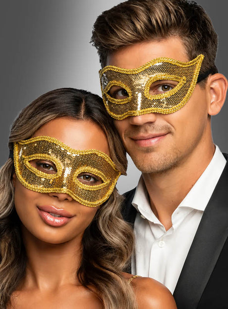 Eine Frau und ein Mann, beide formell gekleidet, posieren eng beieinander vor einem neutralen Hintergrund mit Farbverlauf und tragen dabei goldene venezianische Masken mit Pailletten.
