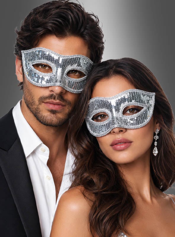 Ein Mann und eine Frau, die eine venezianische Maske mit Pailletten tragen, posieren gemeinsam vor einem grauen Hintergrund mit Farbverlauf.