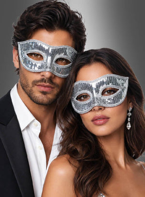 Ein Mann und eine Frau, die eine venezianische Maske mit Pailletten tragen, posieren gemeinsam vor einem grauen Hintergrund mit Farbverlauf.