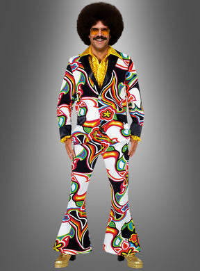 Eine Person, die das Schlagerstar-Kostüm „Neon Psychodelic“ trägt – bestehend aus einem farbenfrohen, gemusterten Anzug im Stil der 1970er Jahre mit Schlaghosen, goldene Schuhe, ein gelbes Hemd, eine große Afro-Perücke und eine Sonnenbrille – steht vor einem schlichten grauen Hintergrund und verkörpert ein auffälliges 70er-Jahre-Disco-Outfit mit lebhaftem neonfarbenem Psychedelic-Flair.