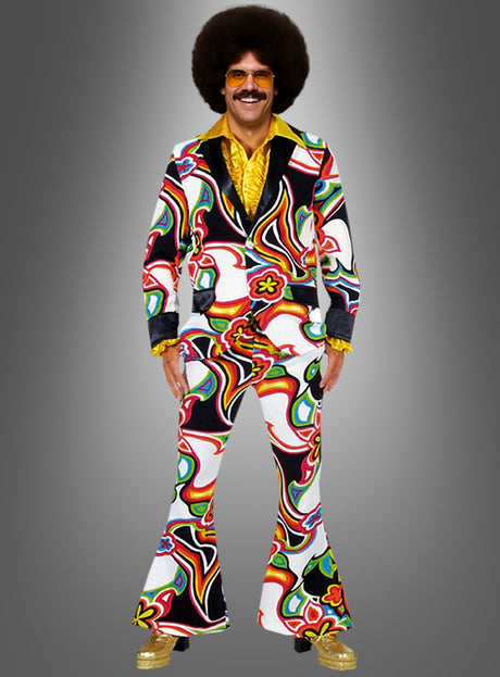 Eine Person, die das Schlagerstar-Kostüm „Neon Psychodelic“ trägt – bestehend aus einem farbenfrohen, gemusterten Anzug im Stil der 1970er Jahre mit Schlaghosen, goldene Schuhe, ein gelbes Hemd, eine große Afro-Perücke und eine Sonnenbrille – steht vor einem schlichten grauen Hintergrund und verkörpert ein auffälliges 70er-Jahre-Disco-Outfit mit lebhaftem neonfarbenem Psychedelic-Flair.
