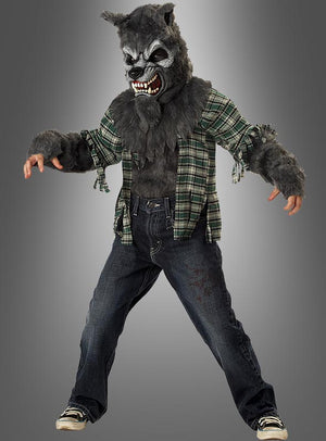 Ein Kind, das das „Kinder-Werwolf-Kostüm“ für Halloween trägt – bestehend aus einer knurrenden Maske, pelzigen Handschuhen, einem karierten Hemd und Jeans –, steht vor einem grauen Hintergrund.
