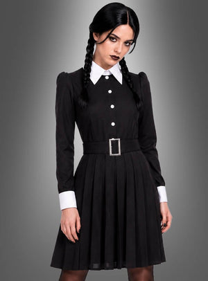 Eine Person mit geflochtenen Haaren trägt das „Düstere Gothic Tochter“-Damenkostüm – ein schwarzes Kleid mit weißem Kragen und Manschetten, kombiniert mit einem schwarzen Gürtel und einer silbernen Schnalle – und steht vor einem grauen Hintergrund mit Farbverlauf, was an den zeitlosen Stil der Addams Family erinnert.