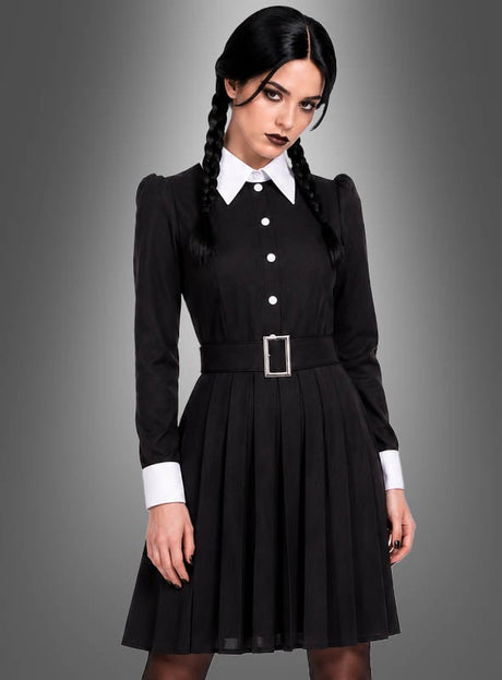 Eine Person mit geflochtenen Haaren trägt das „Düstere Gothic Tochter“-Damenkostüm – ein schwarzes Kleid mit weißem Kragen und Manschetten, kombiniert mit einem schwarzen Gürtel und einer silbernen Schnalle – und steht vor einem grauen Hintergrund mit Farbverlauf, was an den zeitlosen Stil der Addams Family erinnert.