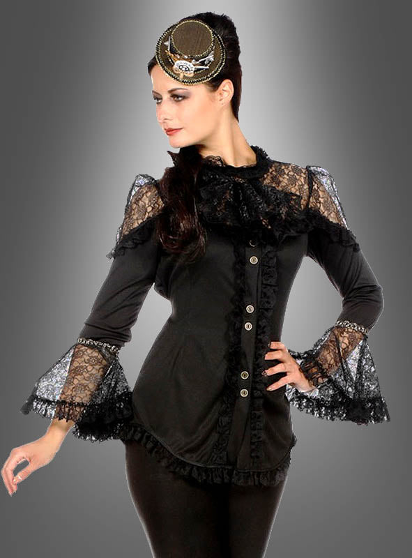 Eine Frau, die die „Elegante Bluse mit Spitze, schwarz“ mit Spitzendetails und ausgestellten Ärmeln trägt, kombiniert mit einer schwarzen Hose und einem dekorativen Kopfschmuck, posiert vor einem grauen Hintergrund mit Farbverlauf.