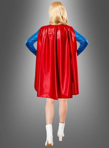 Eine Person, die das Supergirl-Kostüm für Damen von DC Comics trägt – bestehend aus einem blau-roten Anzug mit rotem Umhang und weißen Stiefeln –, steht mit den Händen in den Hüften und dem Rücken zur Kamera.