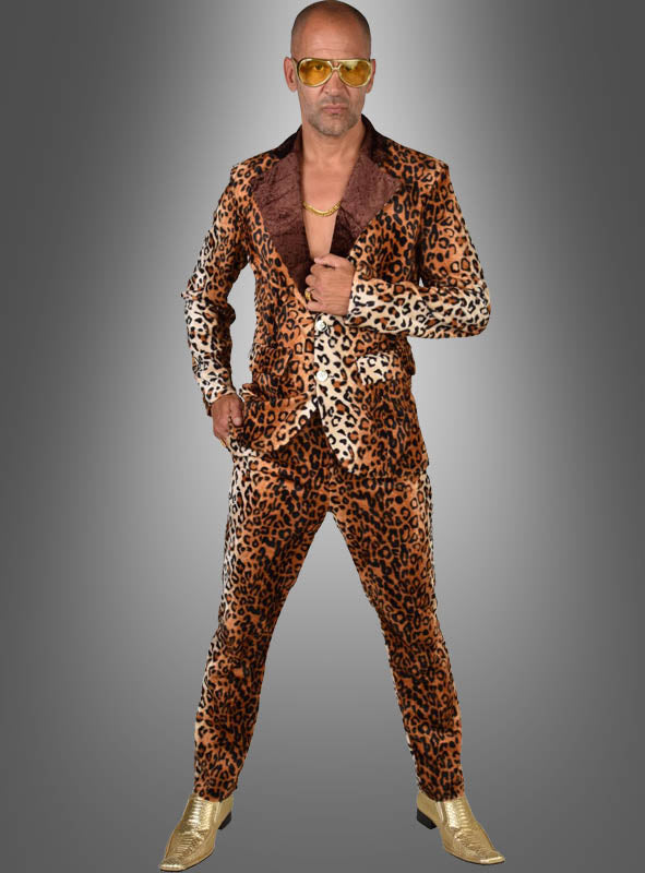 Ein Mann im Zuhälter-Kostüm „Cool Man“ im Leoparden-Look – mit einer goldenen Kette, einer gelben Sonnenbrille und goldenen Schuhen – steht selbstbewusst vor einem grauen Hintergrund und verkörpert den kühnen Stil eines klassischen Zuhälter-Kostüms.