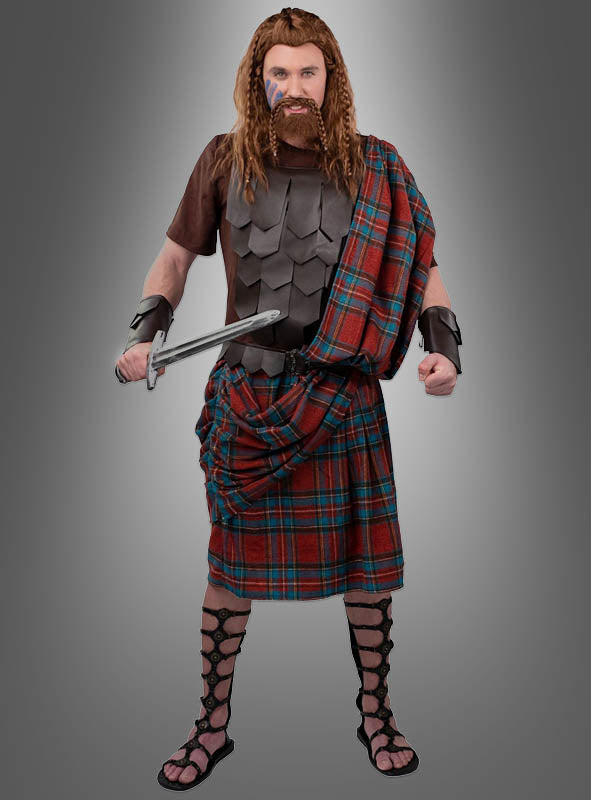 Eine Person in einem Highlander-Schottenkostüm und brauner Rüstung, die ein Schwert in der Hand hält, Handgelenkschützer und Sandalen trägt und vor einem grauen Hintergrund steht – perfekt für ein authentisches Herrenkostüm.