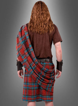 Eine Person mit langen, gewellten Haaren ist von hinten zu sehen. Sie trägt das „Highlander Schotten-Kostüm“, bestehend aus einem roten Tartan-Kilt und einer Schärpe, einem braunen Hemd sowie Manschetten, vor einem grauen Hintergrund mit Farbverlauf.