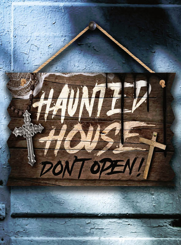 Das Halloween-Schild „Deluxe“ aus Holz (33 x 19 cm) mit der Aufschrift „Haunted House Don’t Open!“ hängt an einer blauen Wand, die mit zwei Kreuzen und Spinnweben verziert ist – die perfekte Ergänzung für deine gruselige Halloween-Deko.