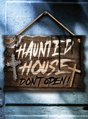 Das Halloween-Schild „Deluxe“ aus Holz (33 x 19 cm) mit der Aufschrift „Haunted House Don’t Open!“ hängt an einer blauen Wand, die mit zwei Kreuzen und Spinnweben verziert ist – die perfekte Ergänzung für deine gruselige Halloween-Deko.