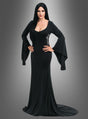 Eine Person steht mit den Händen in den Hüften da und trägt das Morticia-Addams-Kostüm aus „Wednesday“ – ein langes schwarzes Kleid im Gothic-Stil mit ausgestelltem Ärmeln –, dazu glattes schwarzes Haar, vor einem neutralen Hintergrund mit Farbverlauf.
