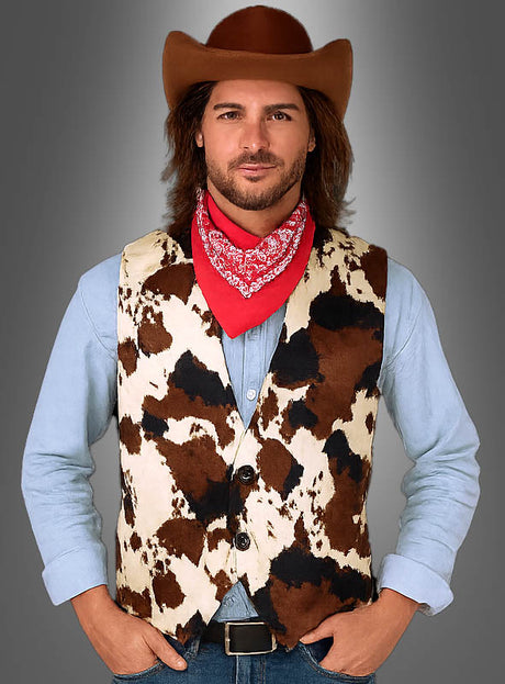 Vor einem grauen Hintergrund steht ein Mann mit den Händen in den Hüften; er trägt einen Cowboyhut, ein rotes Bandana, ein hellblaues Hemd und die Kuhfell-Weste aus der Cowboy-Kollektion.