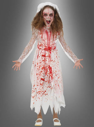 Ein Kind, das das „Zombie Braut“-Kinder-Halloween-Kostüm trägt – bestehend aus einem weißen, blutbespritzten Kleid, Gesichtsbemalung, zerzausten Haaren und einem Schrei mit offenem Mund –, posiert vor einem grauen Hintergrund.