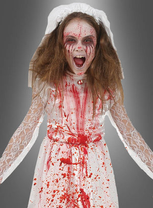 Ein Kind in einem blutbespritzten weißen Spitzenkleid und Schleier, mit zerzaustem Haar und rotem Make-up, schreit vor einem grauen Hintergrund – ein wahrhaft gruseliges „Zombie-Braut-Kinder“-Halloween-Kostüm, perfekt für Halloween.