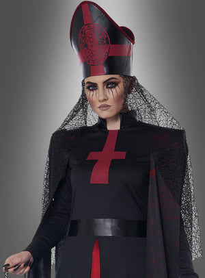 Eine Person, die das Halloween-Kostüm „Dunkle Priesterin“ in Schwarz und Rot trägt – bestehend aus einem großen Hut, Gesichts-Make-up mit schwarzen Strichen und einem Schleier –, steht vor einem grauen Hintergrund.