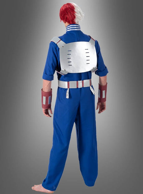 Eine Person im Shoto-Todoroki-Kostüm für Erwachsene aus „My Hero Academia“ – bestehend aus einem blauen Overall, roten und weißen Haaren, einer metallischen Rückenplatte und Handgelenkschützern –, die barfuß mit dem Rücken zur Kamera steht.