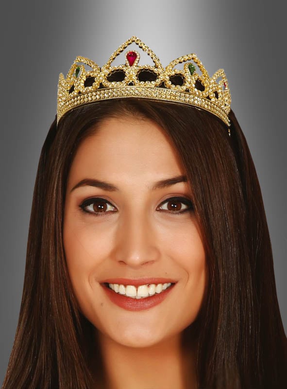 Eine Frau mit glattem braunem Haar lächelt, während sie die „Prinzessin Krone Gold“ vor einem grauen Hintergrund mit Farbverlauf trägt.