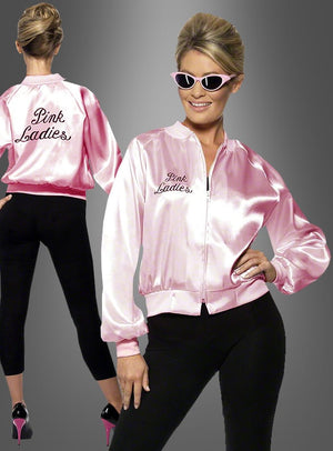 Eine Frau präsentiert die „Pink Lady Jacke Grease 60er Jahre“, kombiniert mit einer schwarzen Hose, High Heels und einer Cat-Eye-Sonnenbrille. Die glänzende rosa Jacke ist sowohl auf der Vorder- als auch auf der Rückseite mit dem Schriftzug „Pink Ladies“ versehen und wird vor einem grauen Hintergrund mit Farbverlauf aus beiden Blickwinkeln gezeigt – perfekt für jedes „Grease“-Kostüm.