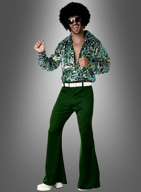 Ein Mann präsentiert die 70er-Jahre-Kleidung „Disco Tino“ – ein grünes Disco-Outfit bestehend aus Schlaghosen, einem gemusterten Hemd, einem weißen Gürtel, einer Sonnenbrille und einer Afro-Perücke – und posiert dabei vor einem grauen Hintergrund; es ist eine kultige Wahl für alle, die auf der Suche nach authentischer Retro-Herrenmode aus den 70ern oder einem Disco-Kostüm für Herren sind.