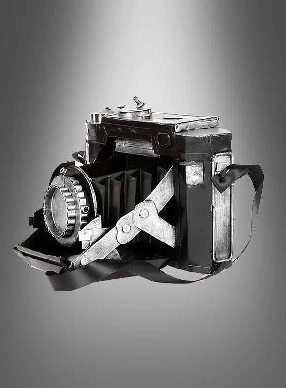 Eine Vintage-Fotokamera-Dekoration aus Blech mit Trageriemen, präsentiert vor einem grau abgestuften Hintergrund, eignet sich ideal als Vintage-Dekorationsstück oder als authentische Vintage-Fotokamera für jedes Kostüm-Ensemble im Stil der 20er Jahre.