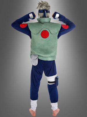 Eine Person in einem Kostüm im Anime-Stil, bestehend aus einer blauen Hose, einer grünen Weste und roten Wirbel-Symbolen, steht barfuß mit dem Rücken zur Kamera vor einem grauen Hintergrund, was an das Kakashi-Kostüm aus dem Naruto-Cosplay erinnert.