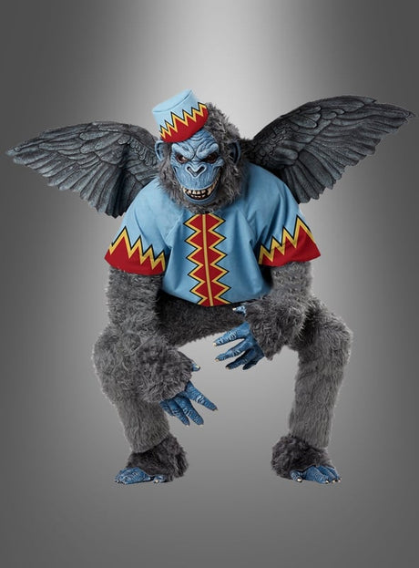 Ein geflügelter Affe mit blauem Gesicht, der einen bunten Hut und ein Hemd mit roten und gelben Zickzackmustern trägt, posiert vor einem grauen Hintergrund mit Farbverlauf und bringt so den verspielten Charme des „Fliegender Affe Märchenkostüm Deluxe“ perfekt zur Geltung.